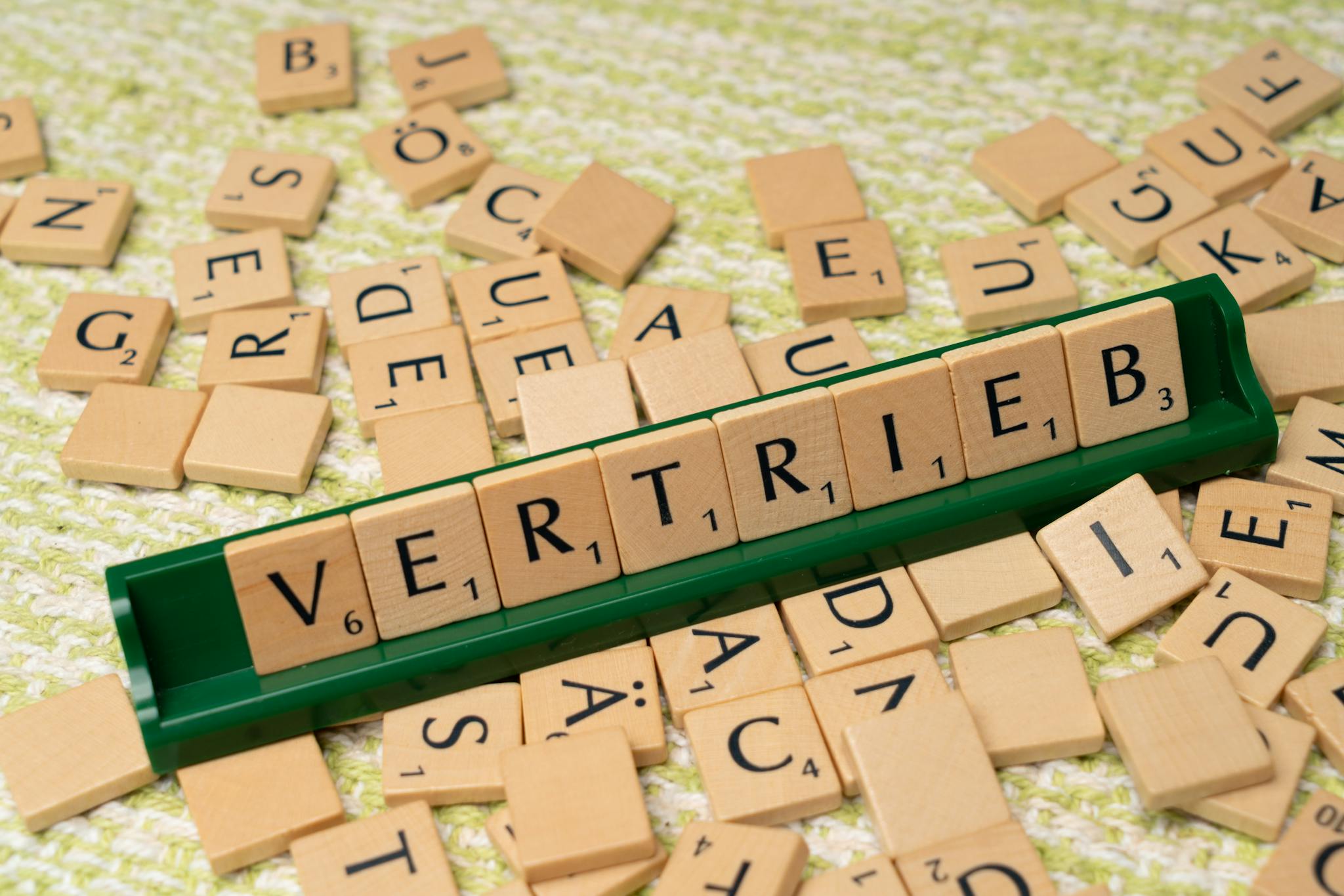 Close-up of Scrabble tiles spelling 'Vertrieb', showcasing language learning and play.